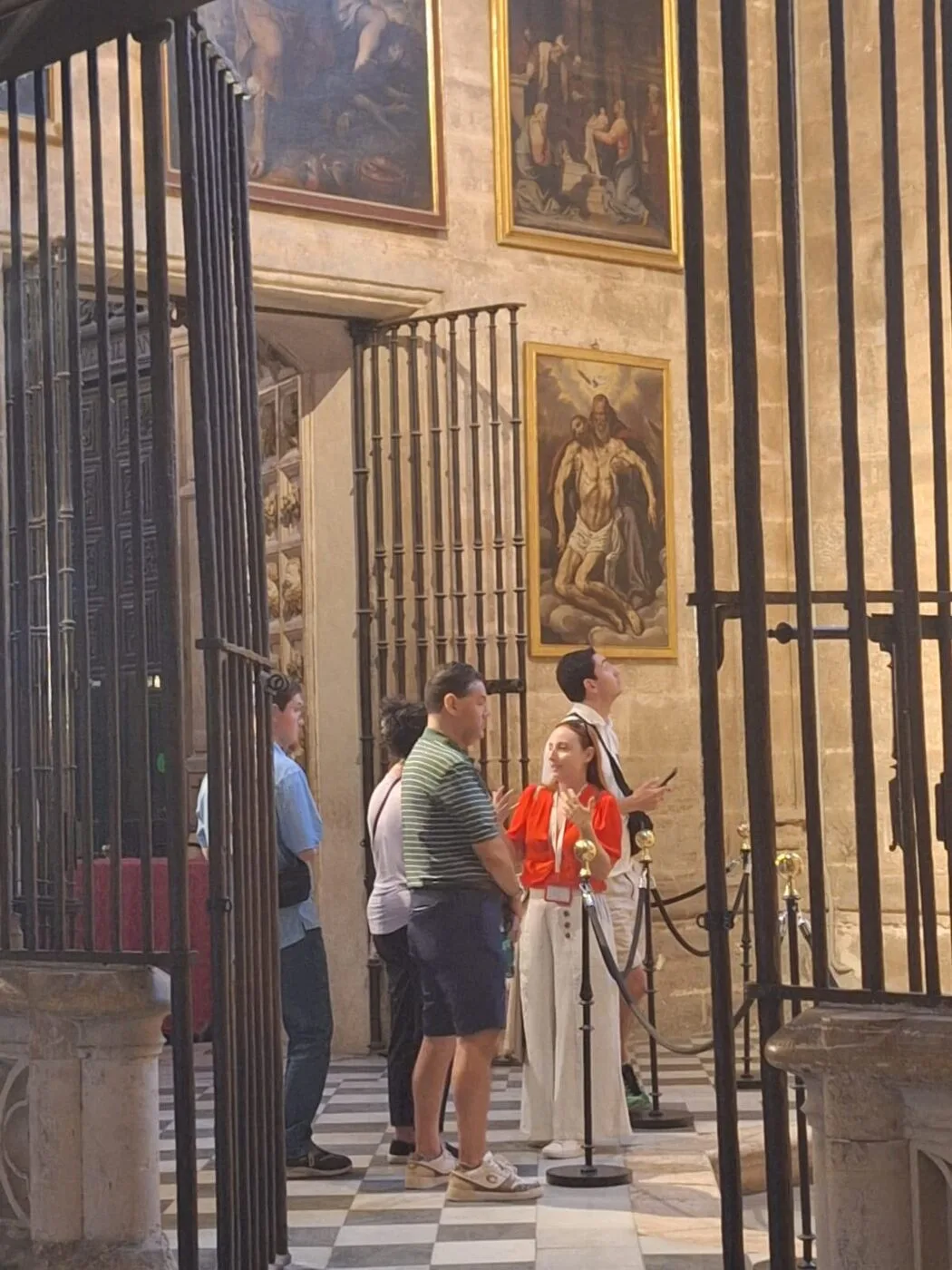 A guide explains the chapel paintings of Seville Cathedral to a group of visitors